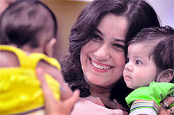 A mother holds her child in her arms as she smiles at another young participant , while awaiting her turn at a baby show in Ludhiana on Sunday