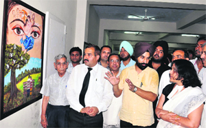 Pritpal Singh Pannu, chairman of the National Integration Forum of Artists and Activists, explains a painting on AIDS to Sessions Judge Raj Rahul Garg in Karnal on Monday.