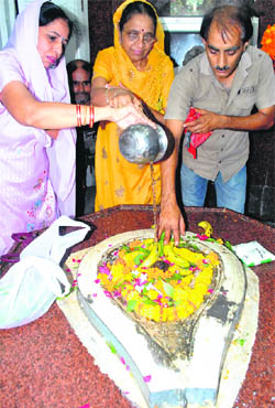 Devotees offer water on a Shivling on the first Monday of Saavan month in a temple in Patiala. 