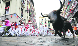 Participants run in front of a Cebada Gago bull during the third bull runof the San Fermin festival in Pamplona on Monday