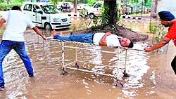 Family members of a patient take him to Government Rajindra Hospital on a waterlogged street in Patiala on Tuesday