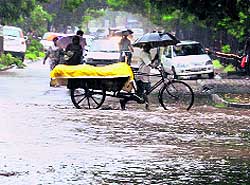 A vegetable vendor crosses a waterlogged road at Sector 21 in Chandigarh on Tuesday