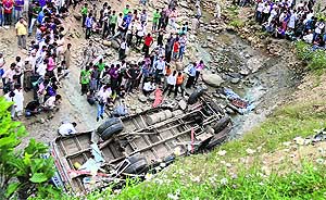 Locals and rescue workers gather around the schoolbus that rolled down a gorge near Gulmarg