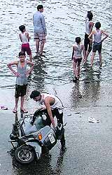 A resident tries to fix his scooter in the Domoria Bridge area