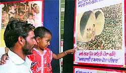 A man and a child see posters during an exhibition at the Civil Hospital in Ludhiana on Wednesday