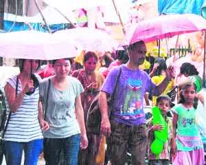 Shoppers with umbrellas walk in rain at Paltan Bazaar in Dehradun on Thursday.  