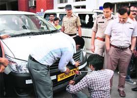 A mechanic affixes a high-security registration plate on a car in Gurgaon on Thursday as Haryana Additional Chief Secretary (Transport) Ramendra Jakhu looks on