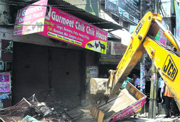 A JCB machine of the Municipal Council demolishes encroachments in Phagwara on Thursday. Photo: Ashok Kaura