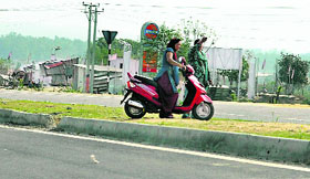 Caring little about the traffic norms, a woman rider risks her life by crossing a divider on the national highway.