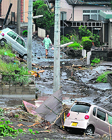 A man walks along a road covered in mud after heavy rains at Kumamoto city in Kyushu island of Japan on Thursday. Fifteen persons have died in flash floods and mudslides. Over 50,000 people have been evacuated. 