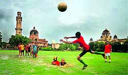 Boys play football at university ground during rain in Allahabad on Friday