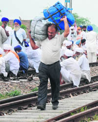 A passenger carries his luggage after the train he was in was stopped near Amritsar on Friday. 