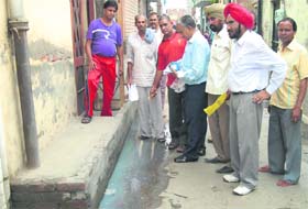 A health team sprays disinfectant in clogged sewerage water at Gandhi Camp in Jalandhar on Saturday