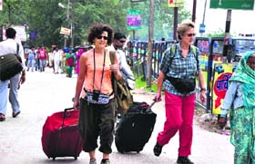 As the entry of vehicles is banned at specific places due to the Kanwar Mela, two foreigners walk to their destination near the CCR Tower-NH 58 stretch in Haridwar on Sunday