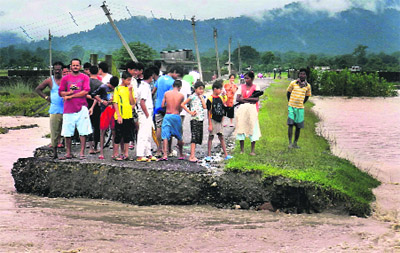 Villagers look at a portion of a road that was washed away in floods near Siliguri on Sunday.