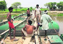 Workers dismantle a pontoon bridge linking Mohar Jamsher village with the mainland