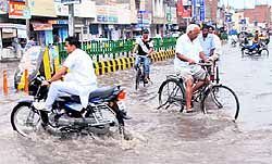 Commuters wade through a waterlogged street in Bathinda after a downpour on Sunday
