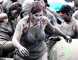 People play in a pool of mud during the 15th Boryeong Mud Festival at Daecheon beach in Boryeong, southwest of Seoul, on Sunday. The annual festival, which runs from July 14-24, aims to encourage the use of mud for cosmetic skin-care and to promote tourism in the region