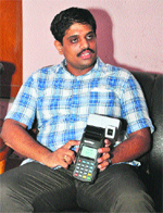 Deputy Commissioner Ajit Balaji Joshi shows a bio-metric device in Jhajjar.