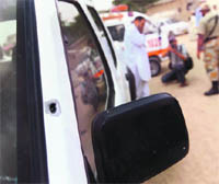 Paramilitary soldiers and police officials stand alongside the UN vehicle attacked in Karachi. 