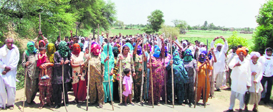 Farmers stand guard to prevent survey teams from entering their fields in Gorakhpur 
