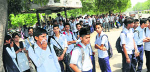 School students wait for a bus at the Sector 18 bus stop in Chandigarh on Thursday. 