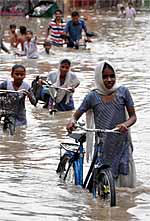 Students (right) wade through a flooded street in Bathinda on Friday