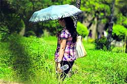 A girl takes cover under an umbrella as sun plays hide and seek in Jammu on Friday