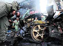 Members of a Thai bomb squad unit inspect the site of a car bomb attack in Thailand on Friday. Two civilians were killed and four wounded in bomb and shooting attacks in southern Thailand, a military spokesman said