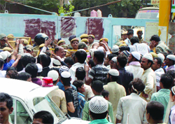 People gather around the mosque site at Subhash Park in Delhi on Saturday as policemen cordon off the area 
