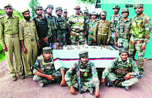 Army and police officers pose with arms and ammunition recovered from a hideout in Mahore on Friday. 