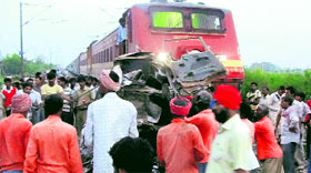 Mangled remains of the truck and rescue workers clearing the railway track.