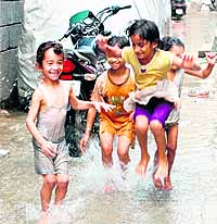 Children enjoy in water, discharged by a tubewell, in an Amritsar street on Sunday