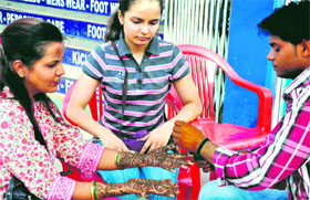 A woman gets mehndi applied on her hands in Haridwar on Sunday.