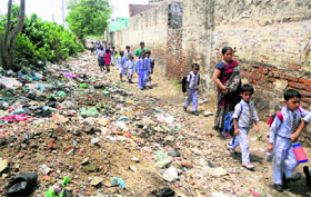 Schoolchildren pass through a street littered with garbage.