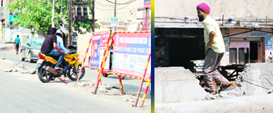Two youths on a motorcycle and a pedestrian cross through broken road dividers on Lawrence Road and Majitha road.