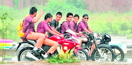 Without bothering to wear helmets, youngsters on motorcycles enjoy in the rain in the New Amritsar area on Monday
