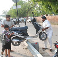 Two men try to take their Scooty across the road divider near Mansa road to escape the jam that obstructed traffic for several hours on Monday