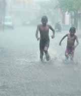 Two boys running through a waterlogged road at Krishna Nagar, Ludhiana. 