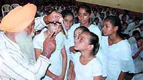 An official from the health department shows the larvae of a mosquito to the students during a dengue awareness programme held at the Arya Model Girls School in Bathinda.