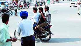 A traffic policeman asks three youths on a motorcycle to stop for driving in violation of the traffic rules. However, the trio managed to flee. A drive has been launched in the city against the traffic rule violators with cops handing out challans and towing away vehicles.