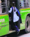 A girl boards a moving low-floor bus. 