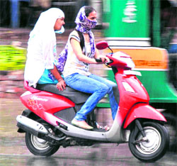 Girls hurry on their scooter to escape the rain that lashed Haridwar on Tuesday afternoon.