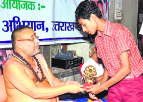 Jagadguru Shankaracharya Raj Rajeshwaram Maharaj gives away a prize to a student, who won a relay race organised in memory of late Prime Minister Chandrashekhar in Haridwar on Tuesday
