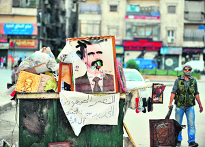 A rebel stands near a vandalised portrait of Bashar al-Assad in Aleppo.