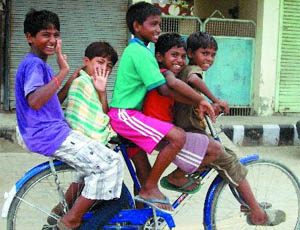 Five children adjust themselves on a bicycle while enjoying a ride on a city street. 