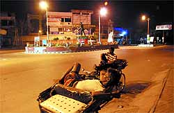 Two rickshaw pullers spend the night reclining on their rickshaws while waiting for passengers at Fauji Chowk in Bathinda