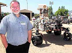 Mars Science Laboratory team chief engineer Rob Manning poses with an engineering model of NASAs Curiosity Mars rover in a sandy, Mars-like environment named the Mars Yard at NASAs Jet Propulsion Laboratory in Pasadena, California, on Wednesday. The real Curiosity rover, part of the Mars Science Laboratory mission, is on its way to the Red Planet, with a planned arrival and landing on August 5