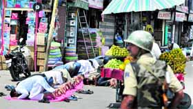 Muslims offer prayers as a policeman looks on during the first Friday of  Ramadan in Srinagar.