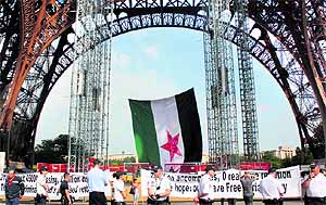 Policemen stand in front of a giant Syrian revolutionary flag, hung by two rebels in support of the Syrian uprising, after they climbed the scaffolding placed under the Eiffel Tower in Paris on Friday